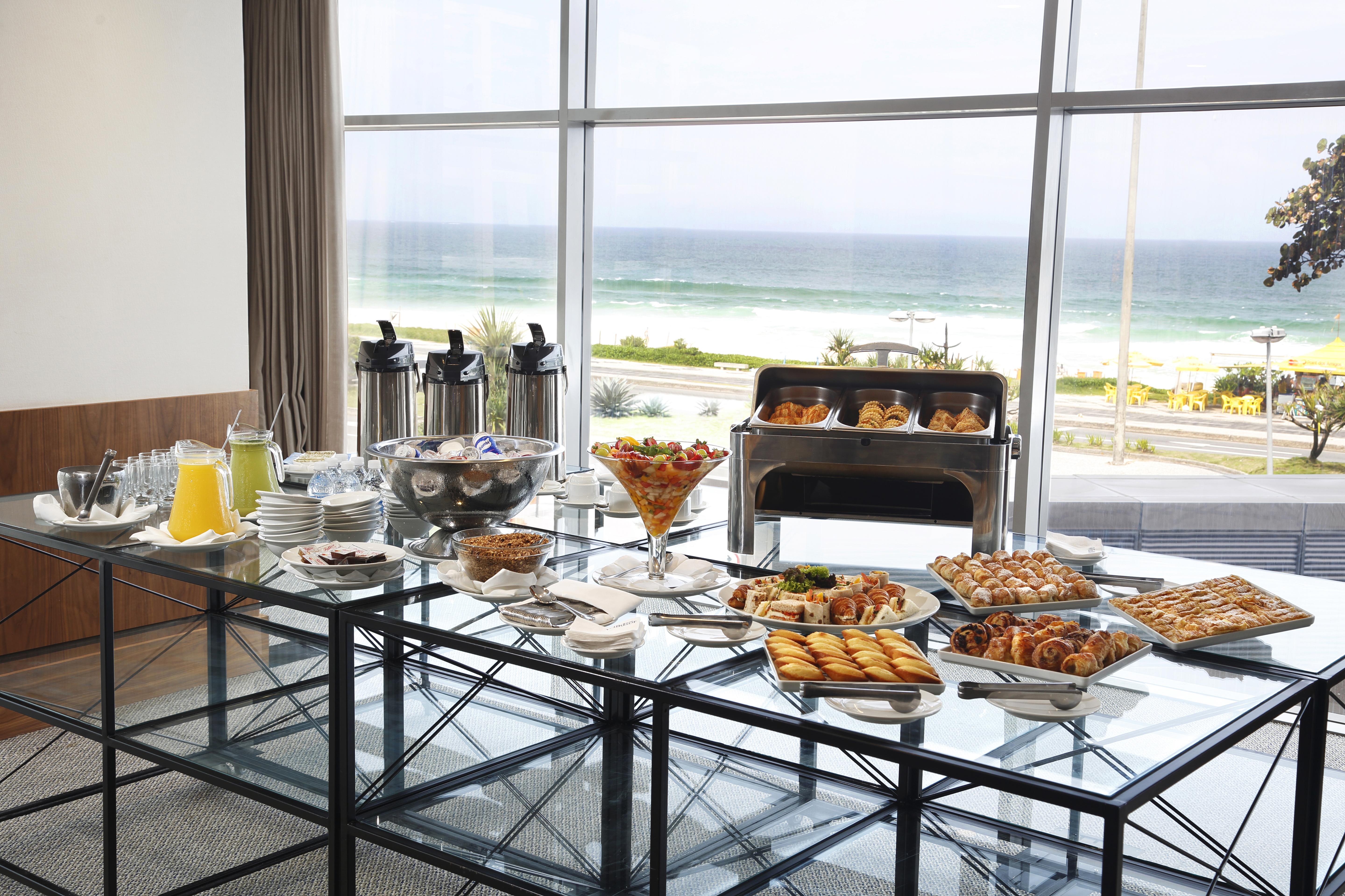 Windsor Marapendi Hotel Rio de Janeiro Exterior foto The photo shows a beautifully arranged buffet table with a variety of food items. In the foreground, there are multiple plates and bowls filled with different dishes, including pastries, fruits, and savory items. There are also drinks available, such